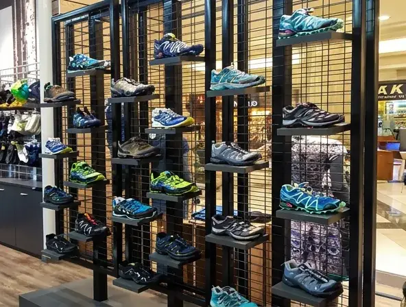 Custom retail footwear display featuring wall-mounted shoe shelving and metal merchandising fixtures in an outdoor apparel store